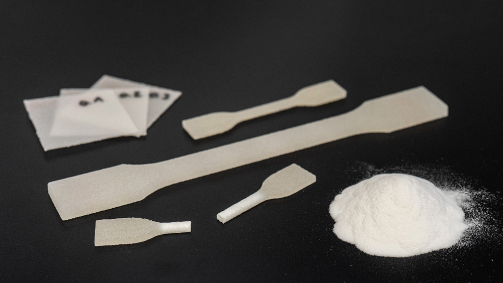 Gedruckte Monolayer (Plättchen), die als schnelle Prozessetablierungsmethode im Projekt eingesetzt werden sollen, Zugstäbe zur Validierung sowie eine Probe des verwendeten PP-Pulvers Rolaserit PP01 von AM Polymers.  Gedruckte Monolayer (Plättchen), die als schnelle Prozessetablierungsmethode im Projekt eingesetzt werden sollen, Zugstäbe zur Validierung sowie eine Probe des verwendeten PP-Pulvers Rolaserit PP01 von AM Polymers.